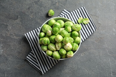 Photo of Bowl of fresh Brussels sprouts and napkin on grey background, top view