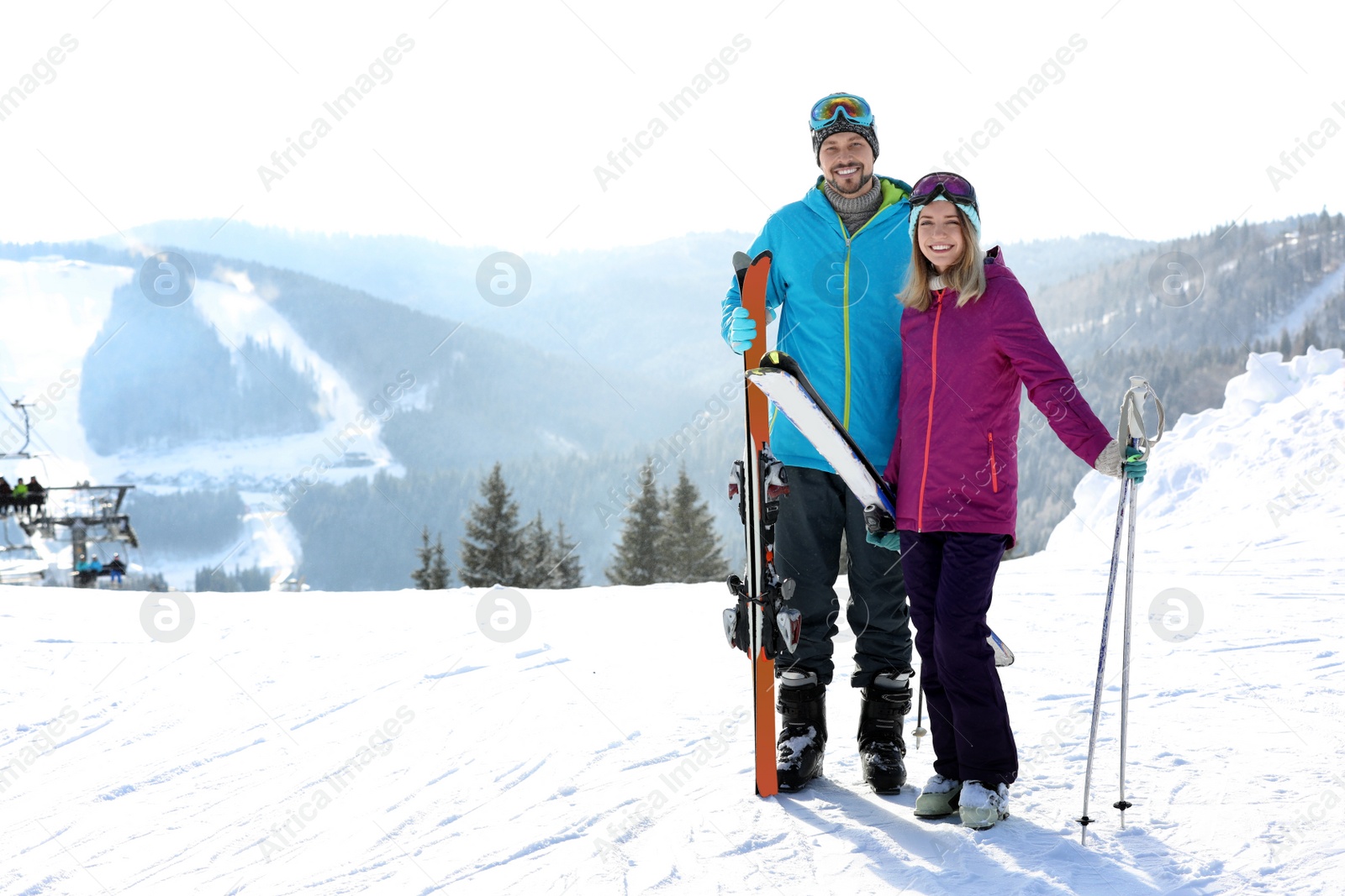 Photo of Happy couple with ski equipment spending winter vacation in mountains. Space for text