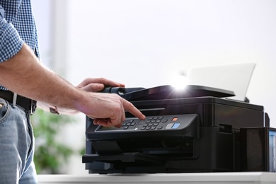 Photo of Employee using modern printer in office, closeup