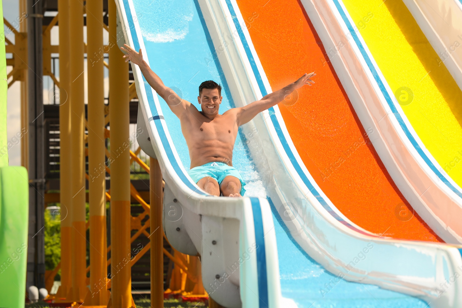 Photo of Man on slide at water park. Summer vacation