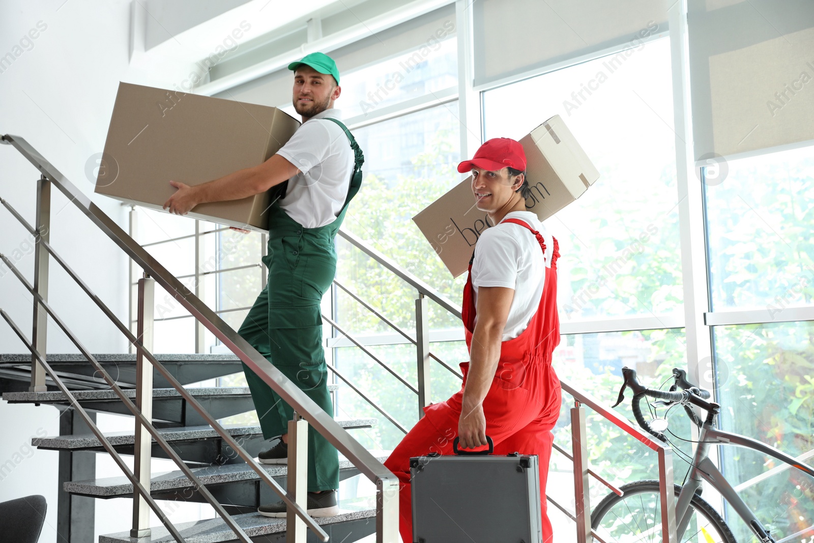 Photo of Male movers carrying boxes in new house