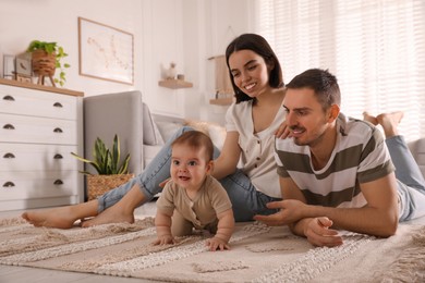 Happy parents watching their cute baby crawl on floor at home