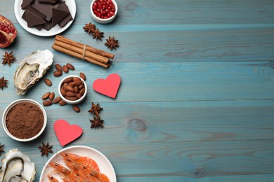 Natural aphrodisiac. Different food products and heart model on light blue wooden table, flat lay. Space for text