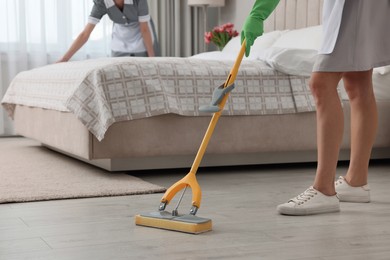 Photo of Professional chambermaids cleaning up bedroom in hotel, closeup