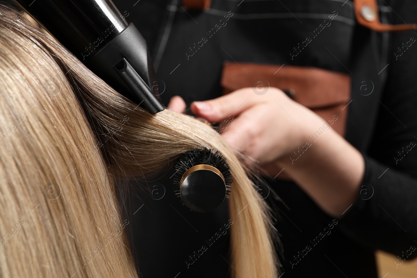 Photo of Hairdresser blow drying client's hair in salon, closeup