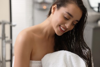 Photo of Smiling woman drying hair with towel after shower in bathroom