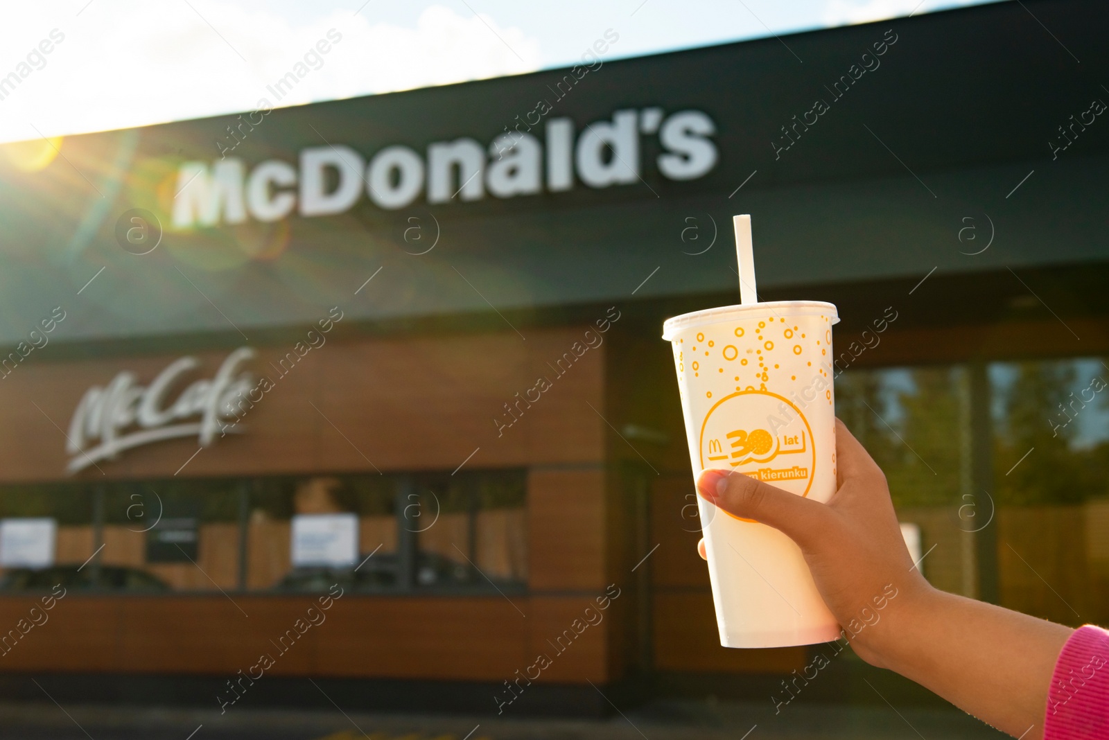 Photo of WARSAW, POLAND - SEPTEMBER 16, 2022: Woman holding cold McDonald's drink near restaurant outdoors, closeup