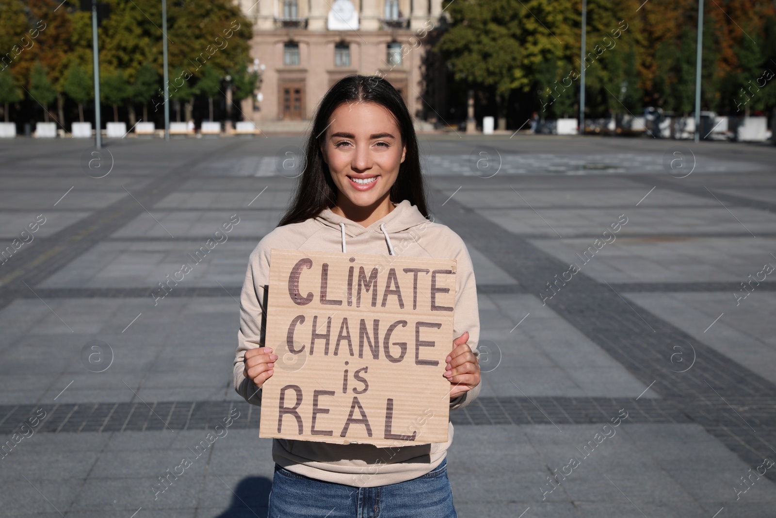 Photo of Young woman with poster protesting against climate change on city street