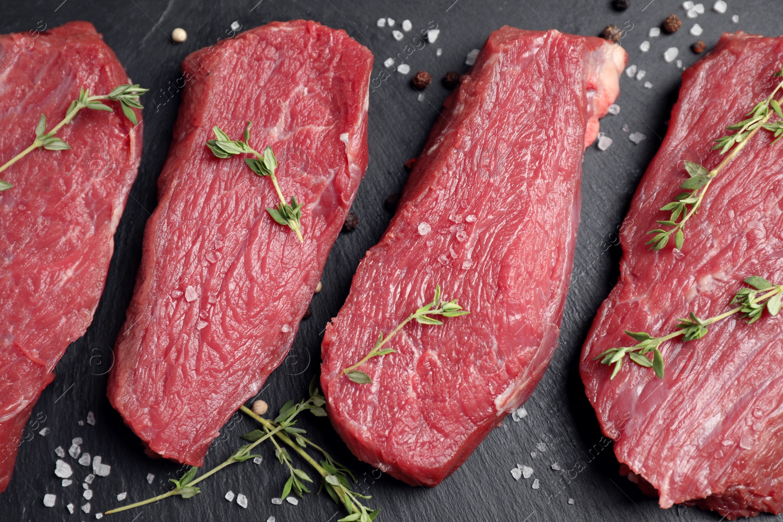 Photo of Flat lay composition with fresh meat steaks on black table