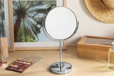 Photo of Mirror, pictures and makeup products on wooden dressing table