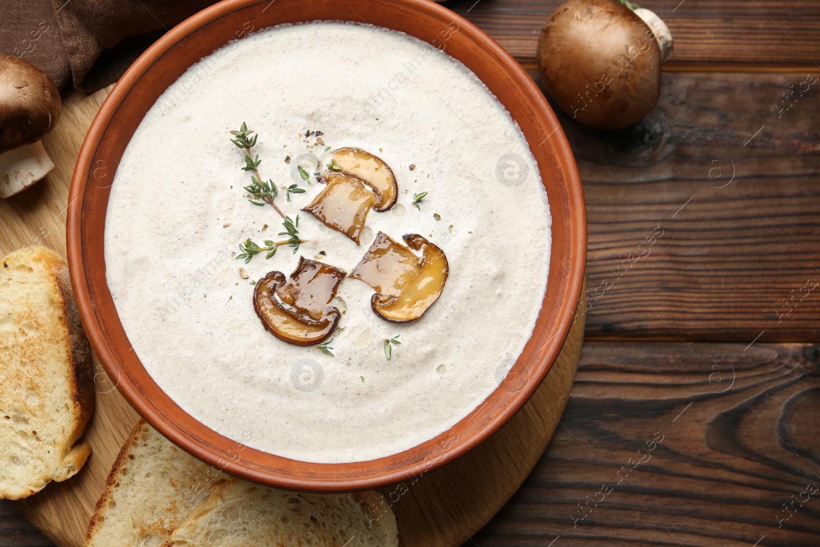 Photo of Fresh homemade mushroom soup in ceramic bowl on wooden table, flat lay. Space for text