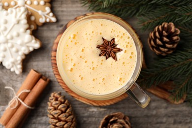 Photo of Glass of delicious eggnog with anise star on wooden table, flat lay