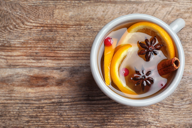 Photo of Aromatic mulled wine on wooden table, top view. Space for text