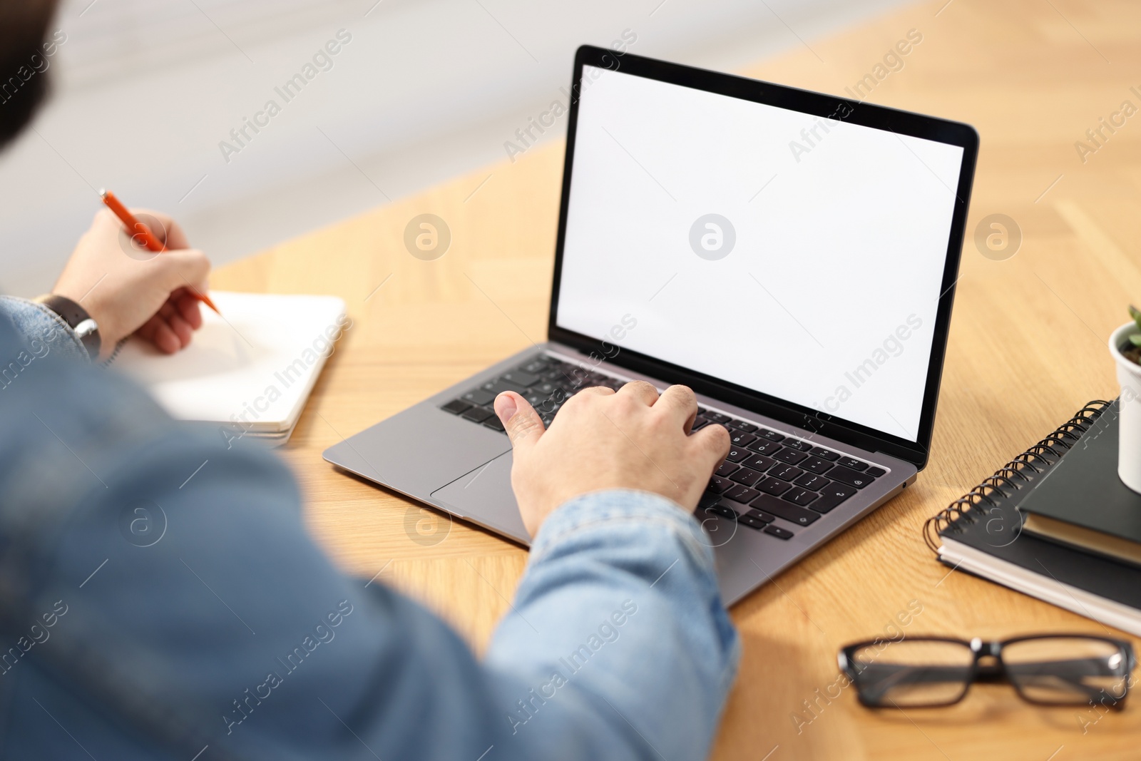 Photo of Young man watching webinar at table indoors, closeup