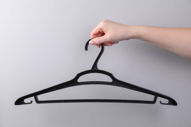 Photo of Woman holding hanger on light grey background, closeup