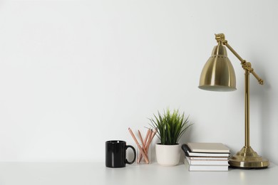 Comfortable workplace with white desk near wall. Space for text