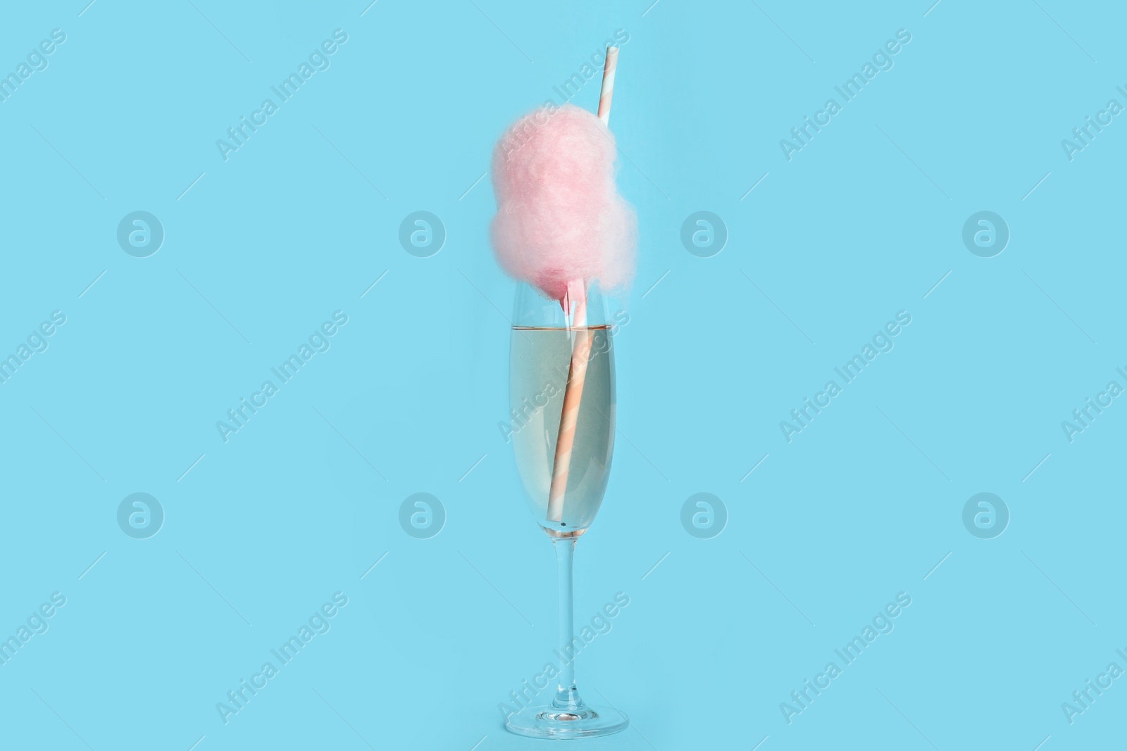 Photo of Cocktail with cotton candy in glass on light blue background