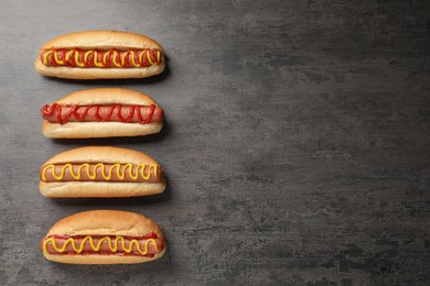 Delicious hot dogs with mustard and ketchup on grey table, flat lay. Space for text