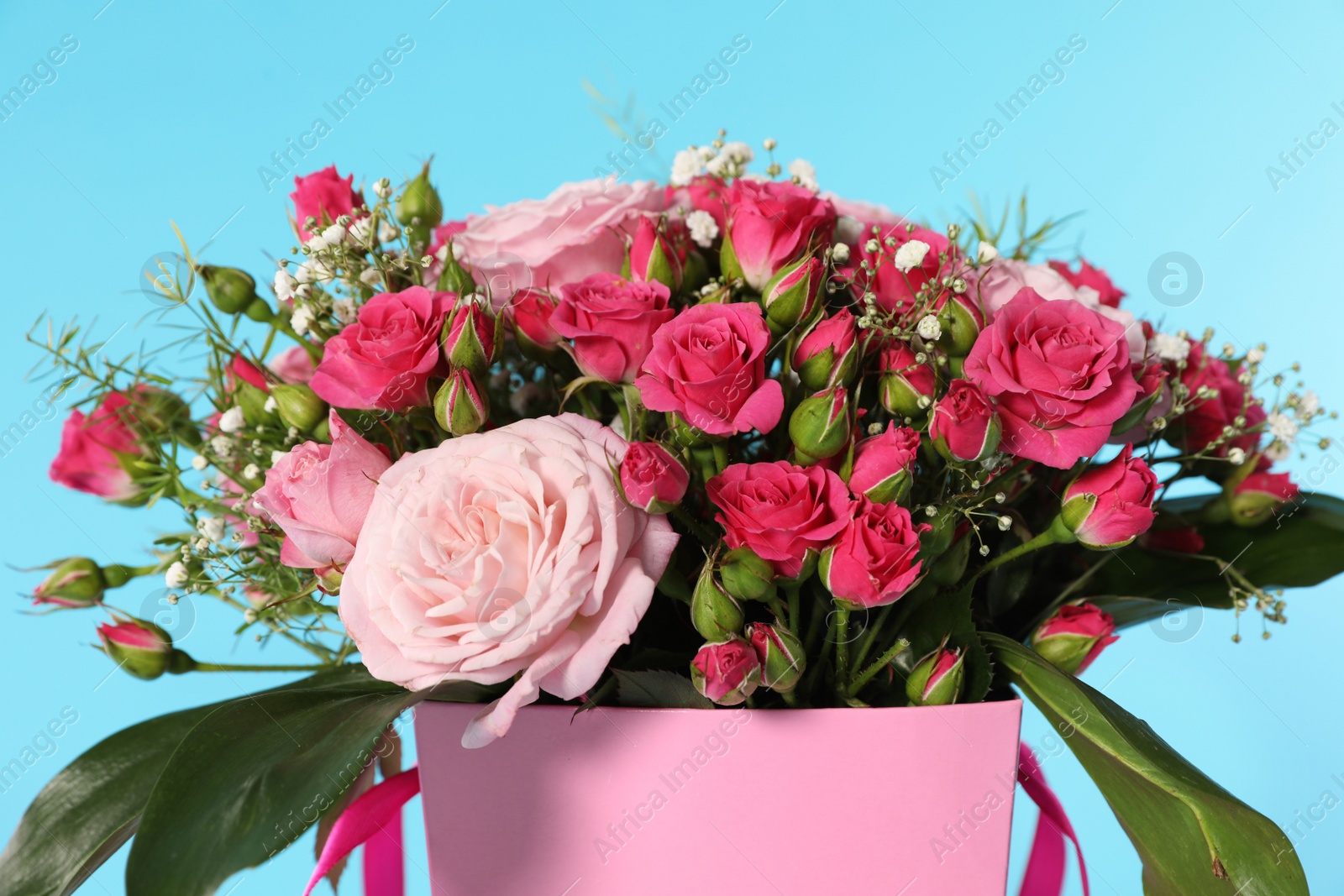 Photo of Beautiful bouquet of flowers in paper gift box on color background