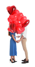 Young couple hiding behind heart shaped balloons isolated on white. Valentine's day celebration