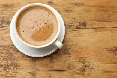 Photo of Cup of aromatic coffee on wooden table, top view. Space for text