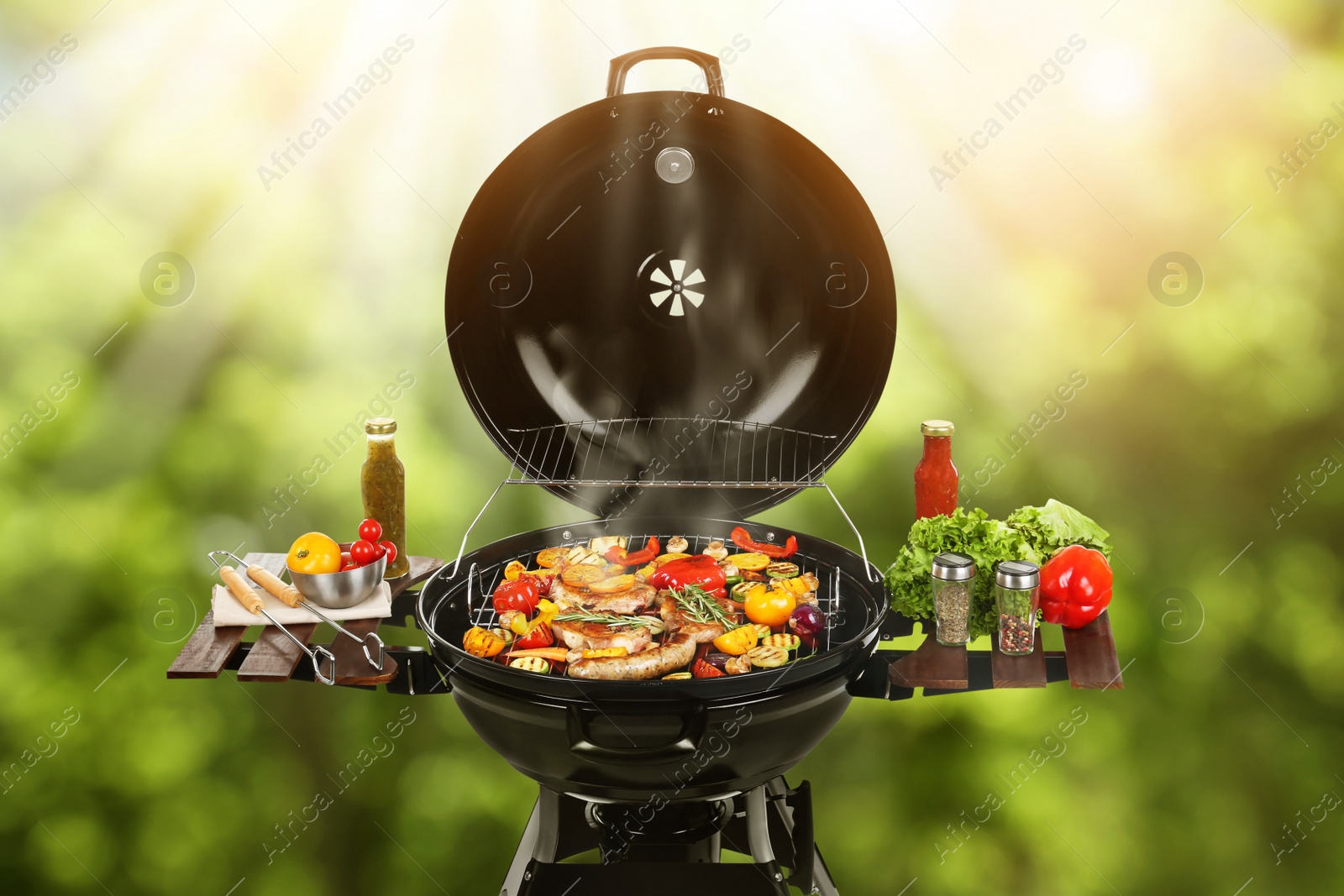 Image of Barbecue grill with meat products and vegetables outdoors on sunny day