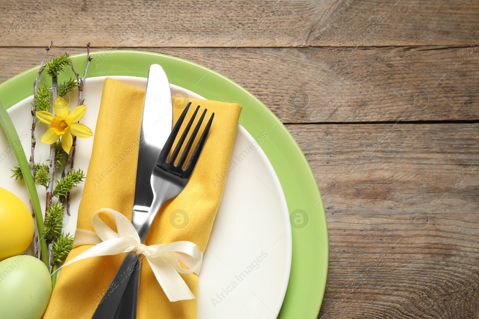 Photo of Festive Easter table setting with beautiful narcissus and painted eggs, top view. Space for text