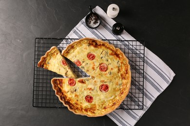 Photo of Delicious homemade cheese quiche and spices on black table, flat lay