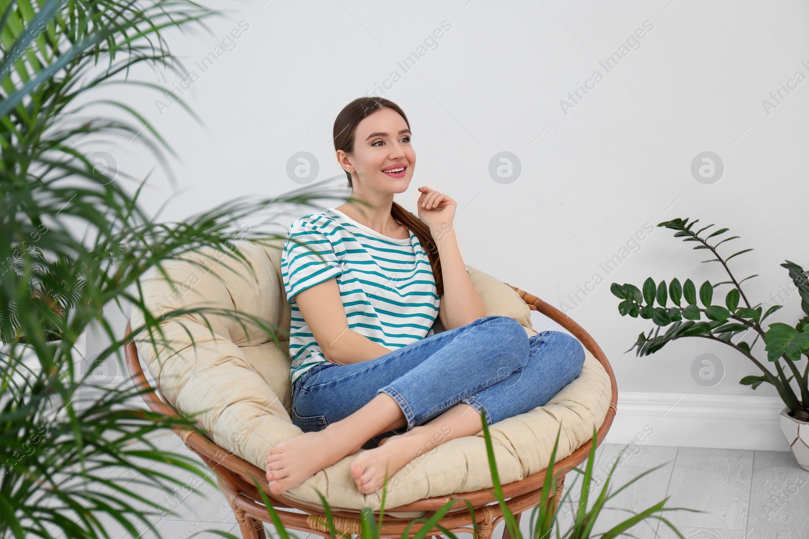 Photo of Young woman in room decorated with plants. Home design