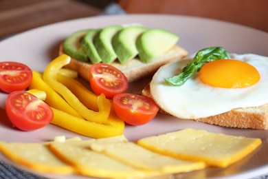 Photo of Tasty toasts with fried egg, avocado, cheese and vegetables on plate, closeup