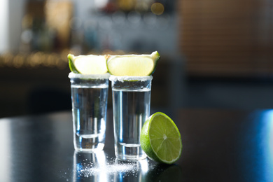 Photo of Mexican Tequila with salt and lime slices on black table at bar