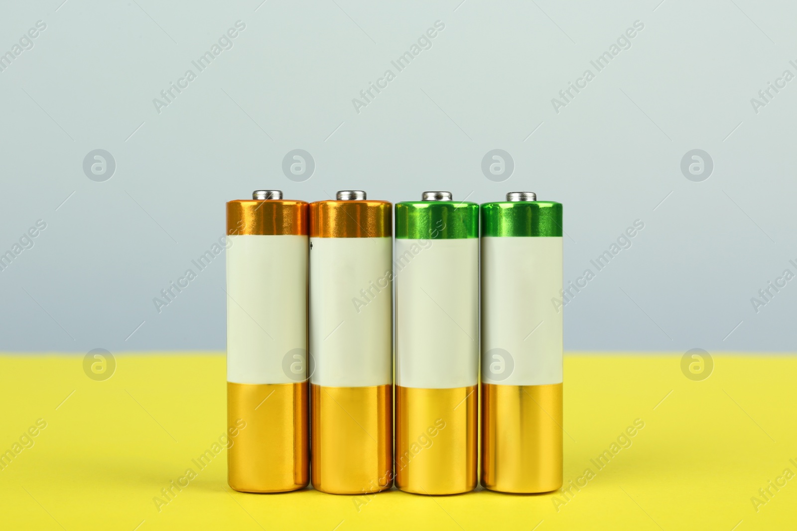 Image of Many new AA batteries on color background