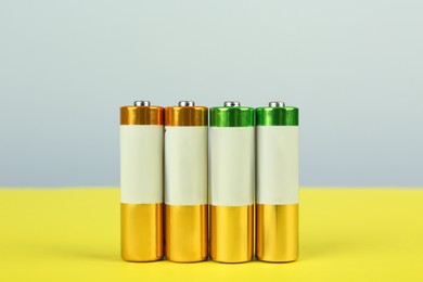 Image of Many new AA batteries on color background