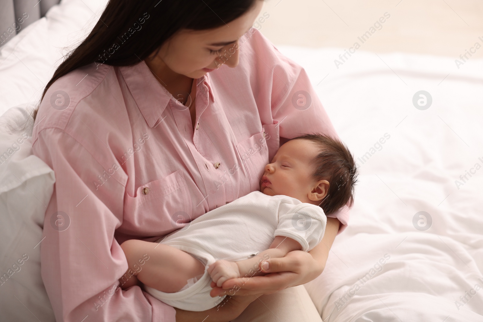 Photo of Mother with her sleeping newborn baby on bed