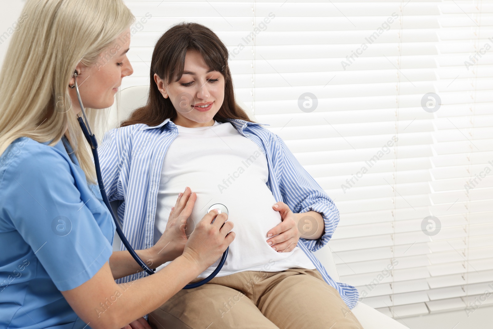 Photo of Pregnancy checkup. Doctor with stethoscope listening baby's heartbeat in patient's tummy in clinic. Space for text