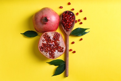 Flat lay composition with ripe pomegranates and wooden spoon on color background