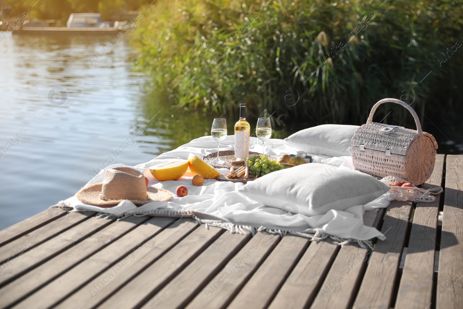 Photo of Picnic blanket with delicious food and wine on pier