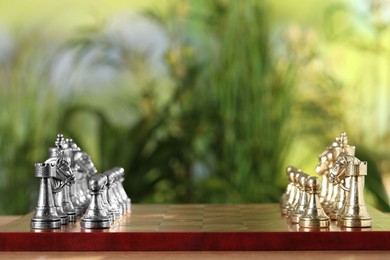 Photo of Golden and silver chess pieces on game board against blurred background. Space for text