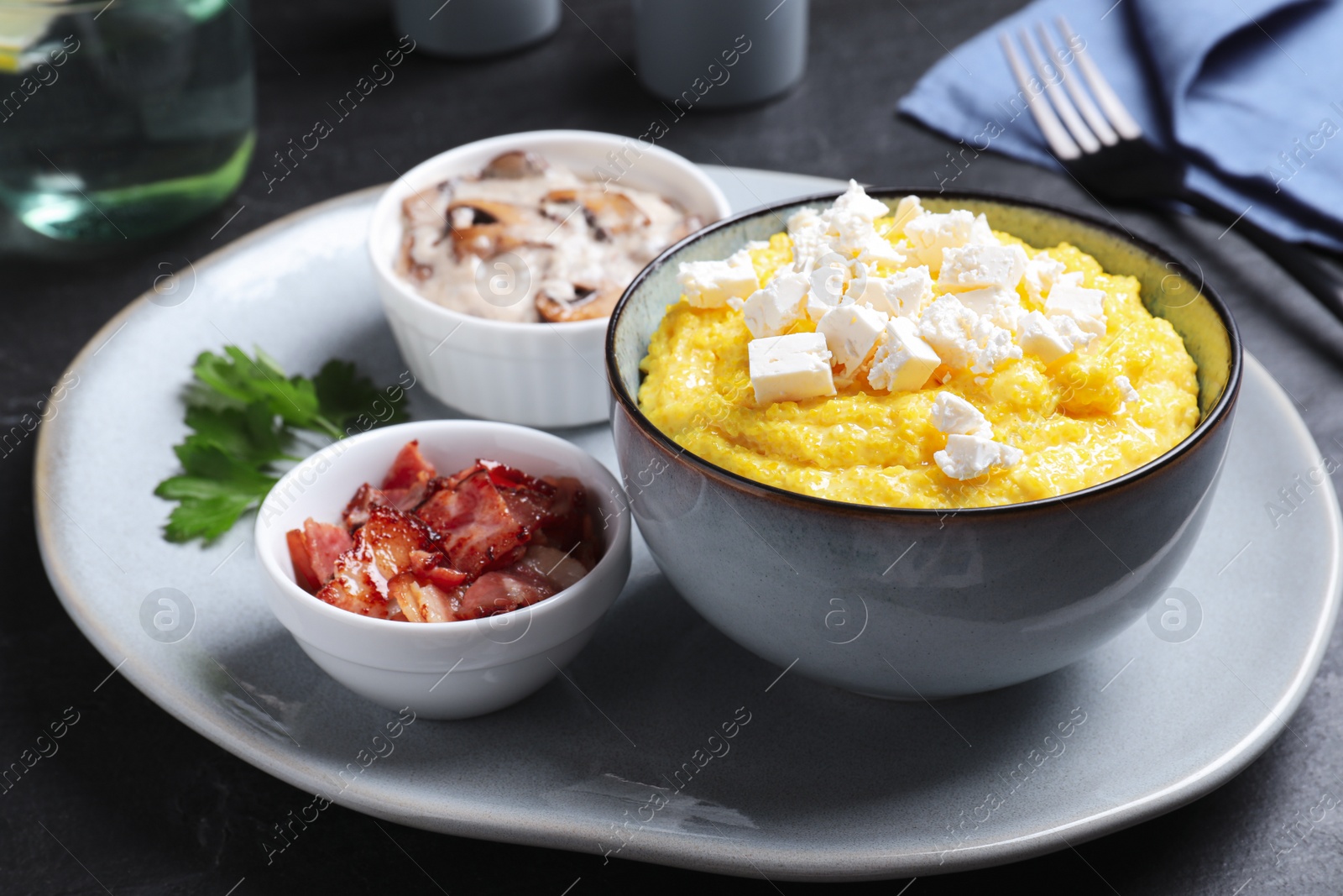 Photo of Tasty banosh served with brynza, pork cracklings and mushrooms on dark table. Traditional Ukrainian dish