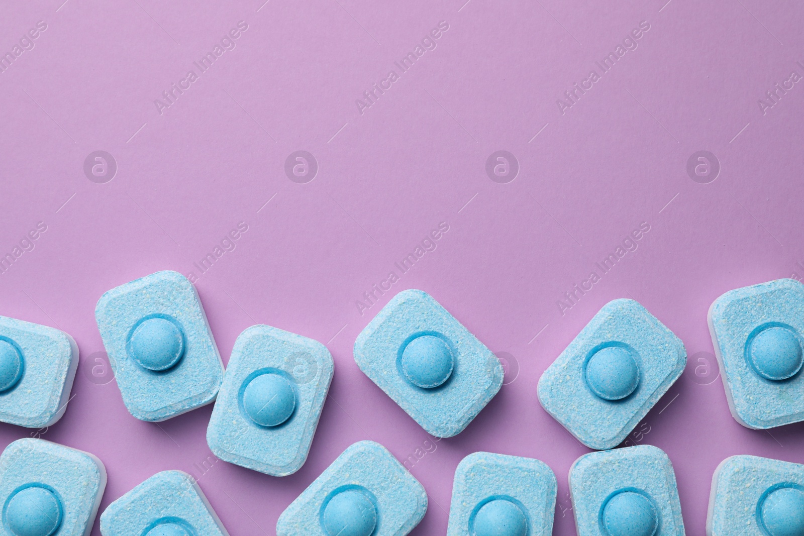 Photo of Water softener tablets on violet background, flat lay. Space for text