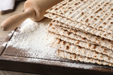 Photo of Stack of matzos and rolling pin on wooden board, closeup