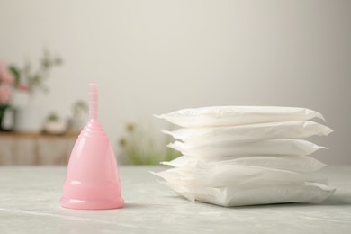 Menstrual cup and pads on grey table