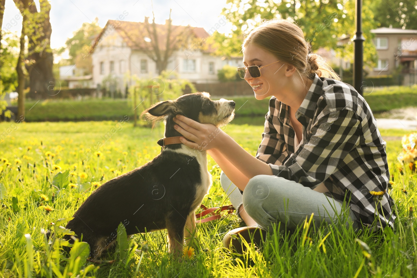 Photo of Teenage girl with her cute dog resting on green grass in park