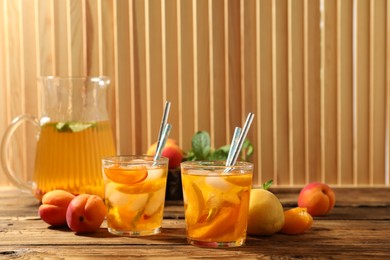 Photo of Delicious refreshing drink with apricot on wooden table
