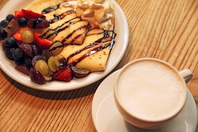 Photo of Cup of aromatic coffee and delicious desserts on wooden table, closeup