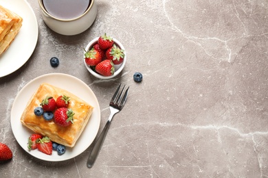 Fresh delicious puff pastry with sweet berries on grey marble table, flat lay. Space for text