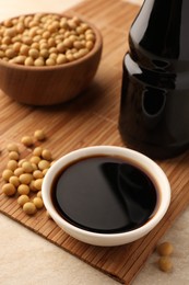 Soy sauce in bowl and soybeans on bamboo mat