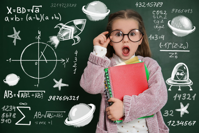 Cute little child in glasses near chalkboard with constitutive equations. First time at school