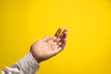 Man holding something in hand on yellow background, closeup