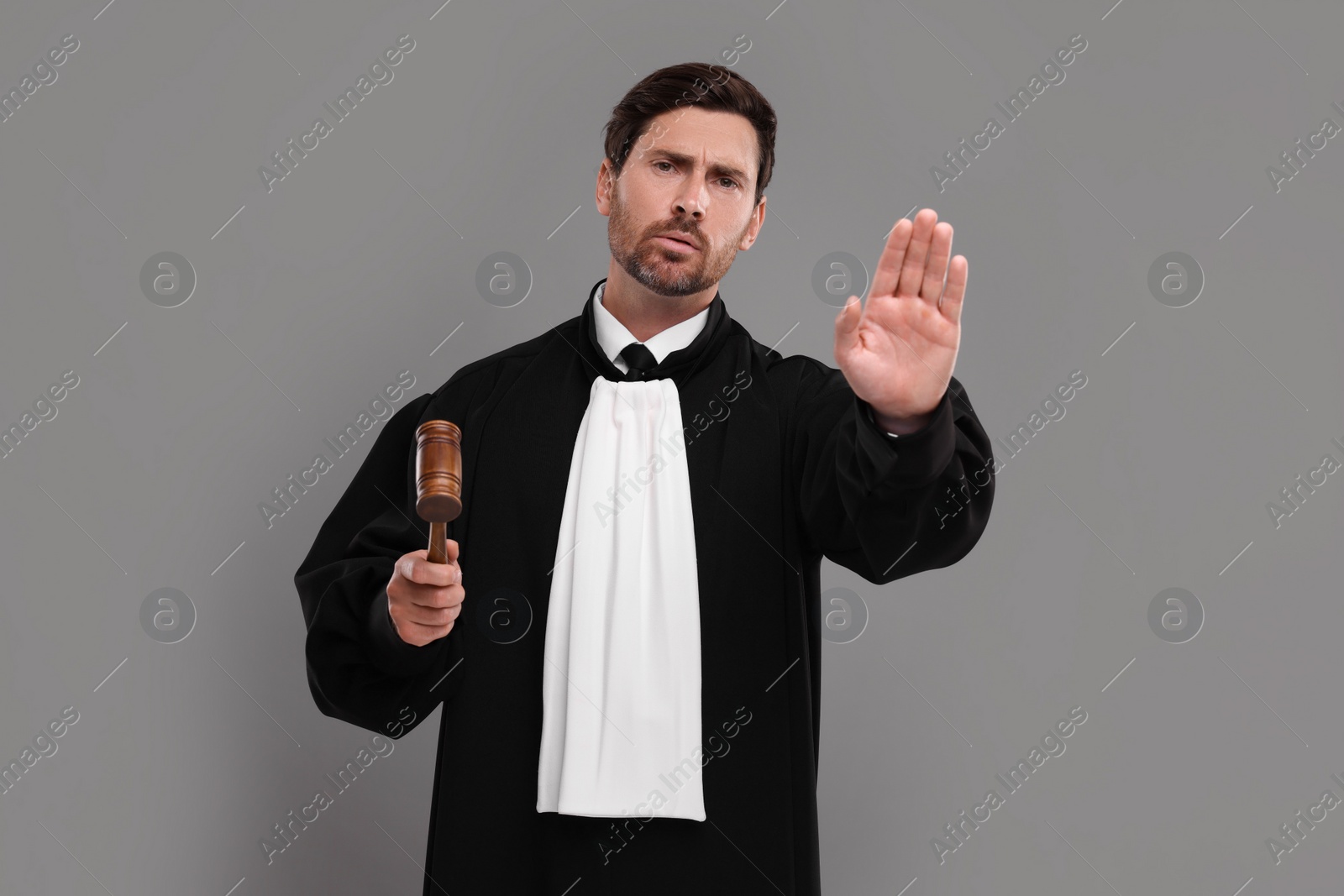 Photo of Judge with gavel gesturing on grey background